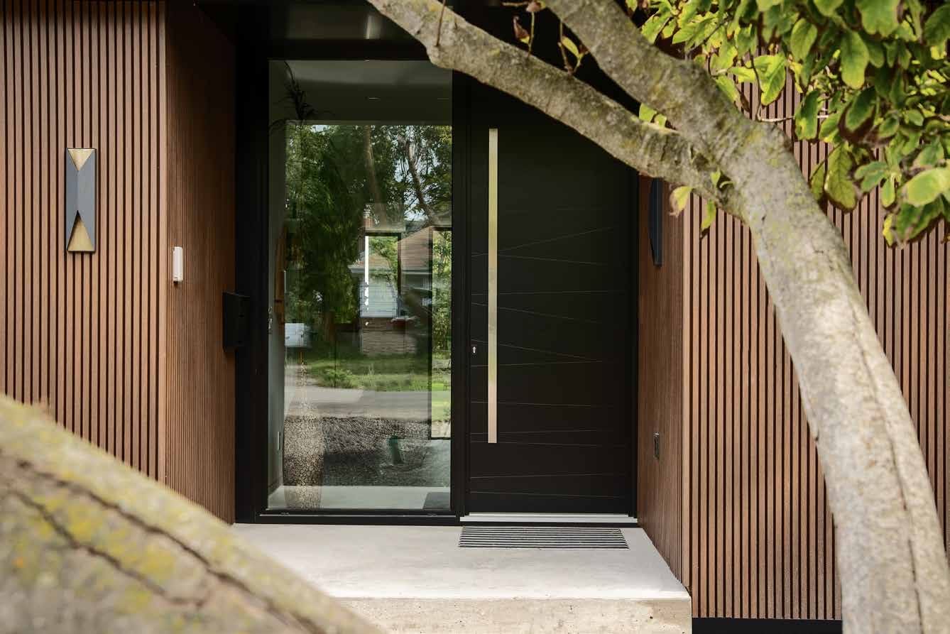 Black solid panel entry door with side glazing and a wood slat wall