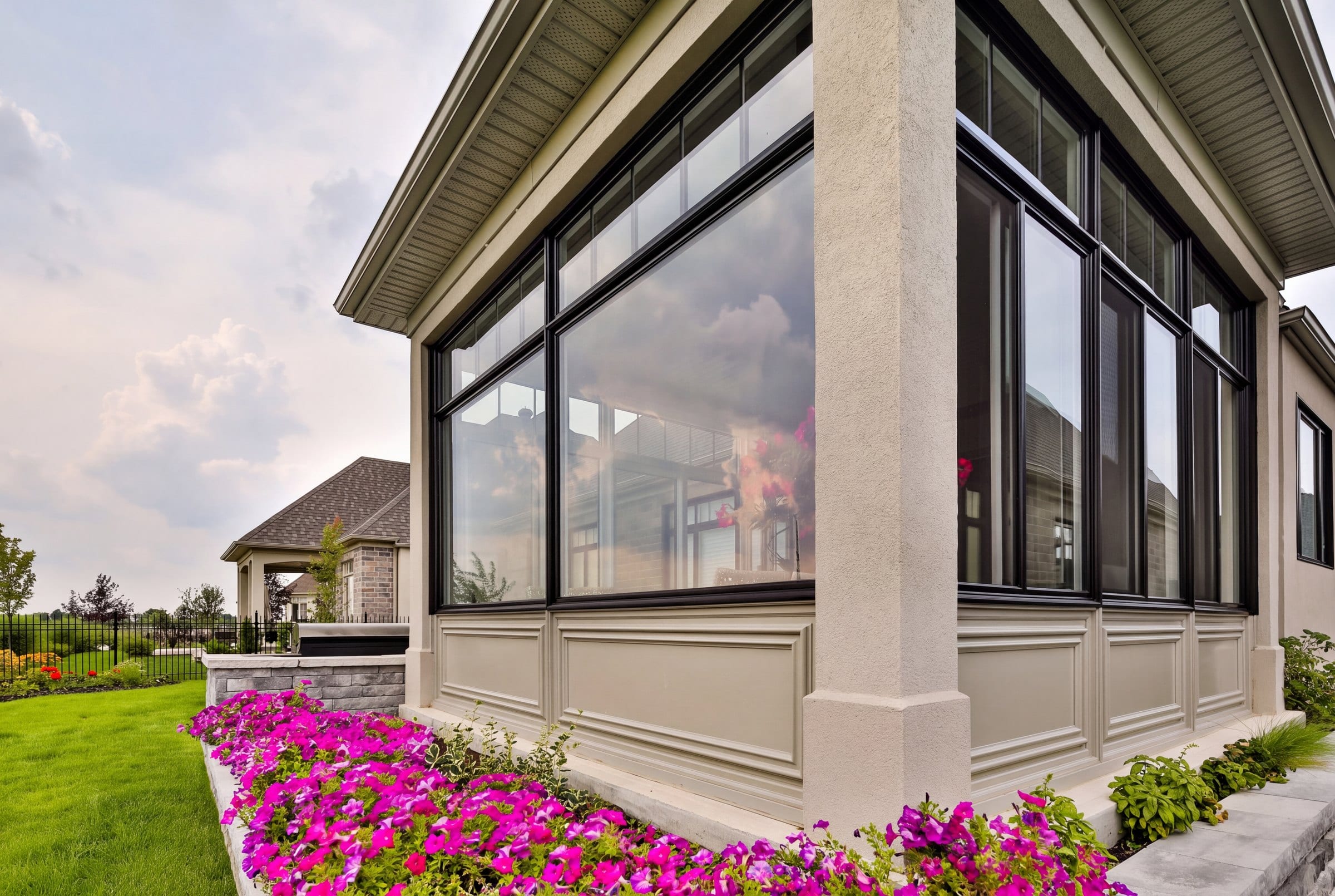 Black framed sliding windows set on a knee wall at the corner of a home's glazed sunroom