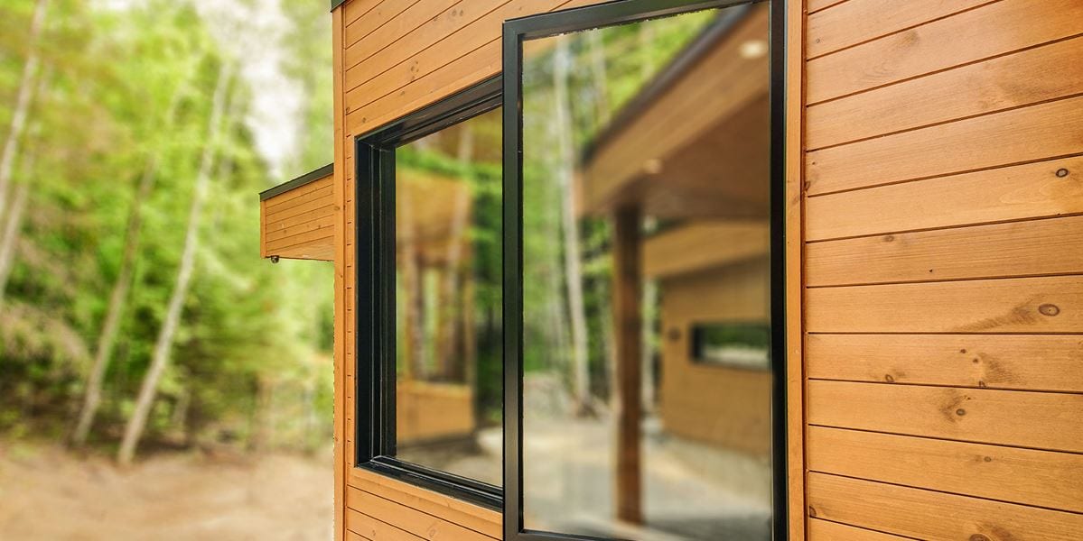 Black casement window open on a wood-clad home