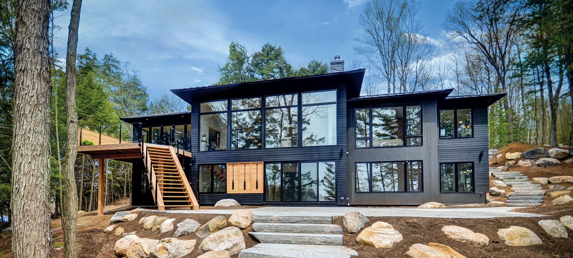 Black contemporary home in the woods with large fixed windows