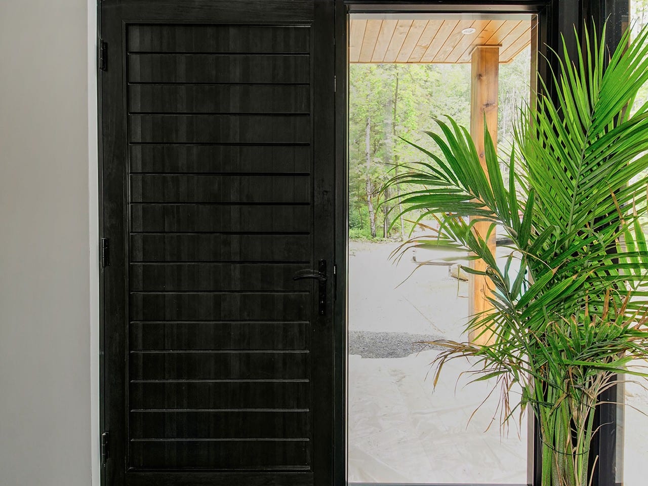Porte d’entrée contemporaine en bois noir à lignes horizontales et latéral vitré, vue de l’intérieur