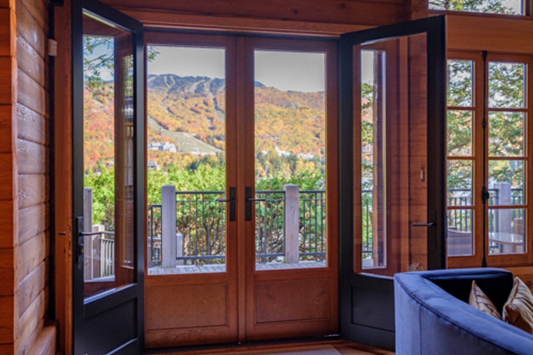Wood french door open onto a deck with autumn mountains