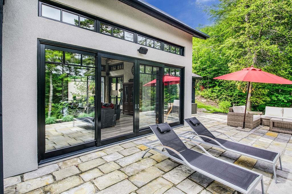 Black-framed lift-and-slide door opening onto a sunny patio