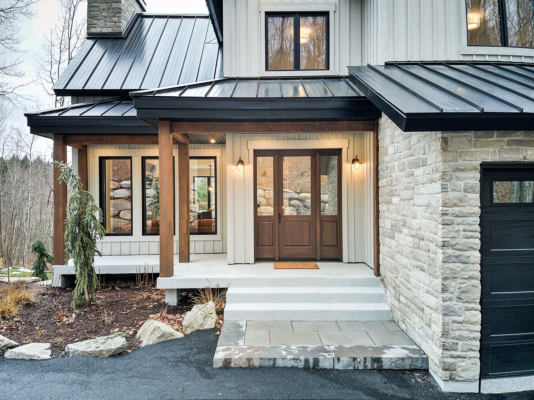 Porte d'entrée de bois vitrée installée par PFA, façade de pierre et revêtement blanc